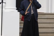 22 a navy and white t-shirt, a black pleated midi skirt, a navy bomber jacket, red trainers and a red crossbody bag