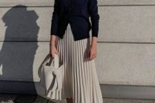 23 a navy cardigan, a creamy pleated midi skirt, grey trainers and a creamy bucket bag for a fashion statement