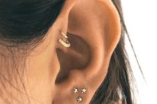 27 a glam curated ear with a multiple lobe piercing with star studs and a double forward helix piercing with gold hoops