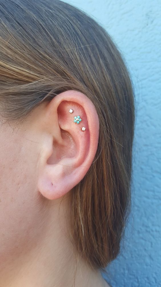a triple flat piercing with two rhinestone and a single floral stud is a cool and stylish idea to rock