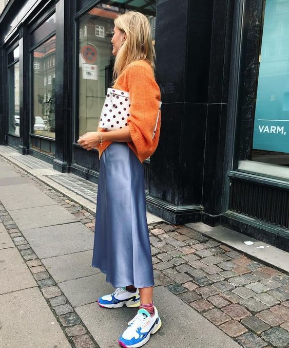 an orange jumper, a blue slip midi skirt, colorful trainers and a polka dot clutch won't let you pass unnoticed