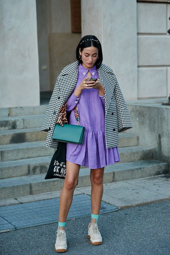a trendy look with a Very Peri knee dress with buttons, neutral trainers and turquoise socks, a printed coat and a dakr green bag