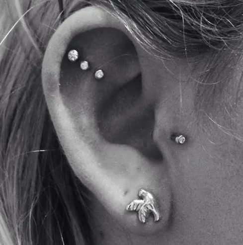 chic ear styling with a triple flat, a tragus and a lobe piercing, with matching rhinestone studs and a bird stud