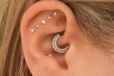 34 creative ear styling with a triple flat, daith, conch and lobe piercing, with heart and arrow studs and a rhinestone hoop