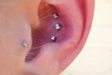 37 a stylish ear with a triple conch piercing, a tragus one done with rhinestone studs and a pearl in the lobe is a bold and chic idea with a touch of classics