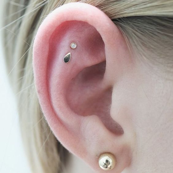 very delicate and subtle ear styling with a lobe piercing and a double flat one, with gold studs that compose a lovely set
