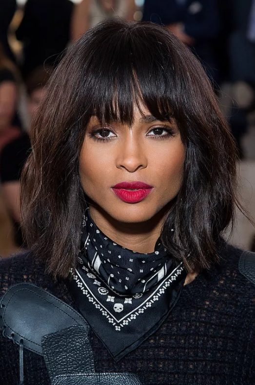 Ciara wearing a shaggy shoulder-length bob with messy waves, textured blunt bangs that accent her impressive cheekbones
