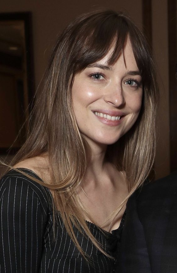 Dakota Johnson rocking long brown hair with an ombre effect and wispy Birkin bangs looks cool and great