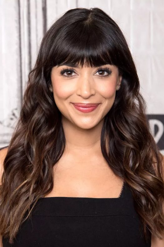 Hannah Simone's straight-across blunt bangs with her long hair highlights the structure in her heart-shaped face