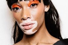 Winnie Harlow’s blunt bangs gradually shorten at the center of her face, highlighting her eyes