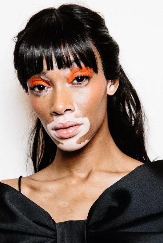 Winnie Harlow's blunt bangs gradually shorten at the center of her face, highlighting her eyes