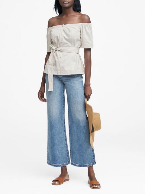 With blue flare cropped jeans, beige and dark gray wide brim hat and brown leather flat sandals