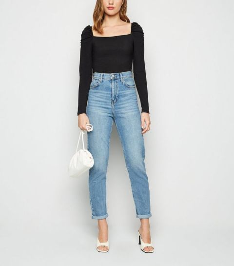With high-waisted cuffed jeans, white leather bag and white high heeled mules
