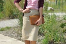 With purple cardigan, beige knee-length skirt, brown leather clutch and beige pumps