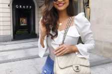 With rounded sunglasses, blue high-waisted shorts and beige leather chain strap bag