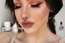 a bold makeup with pink smokeys and a septum piercing with a statement black rhinestone hoop earring