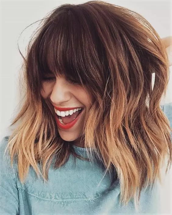 a brown layered long bob with copper highlights and with classic and face framing bangs is a super chic and bold idea
