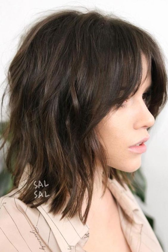 a dark brown long bob with side bangs and messy waves is a cool and modern solution to rock