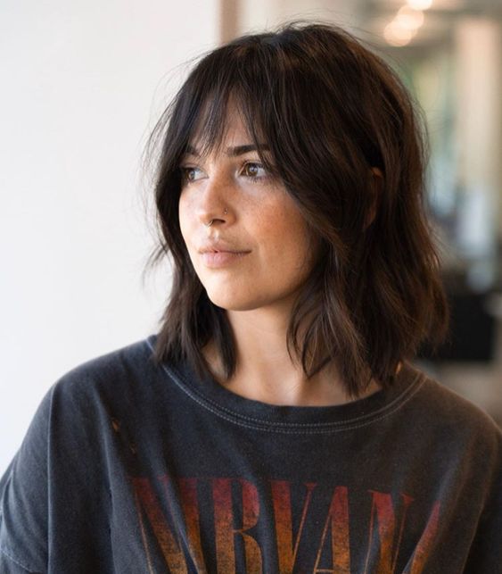 a dark brown messy wavy shoulder length bob with wispy Birkin bangs is a chic and beautiful solution