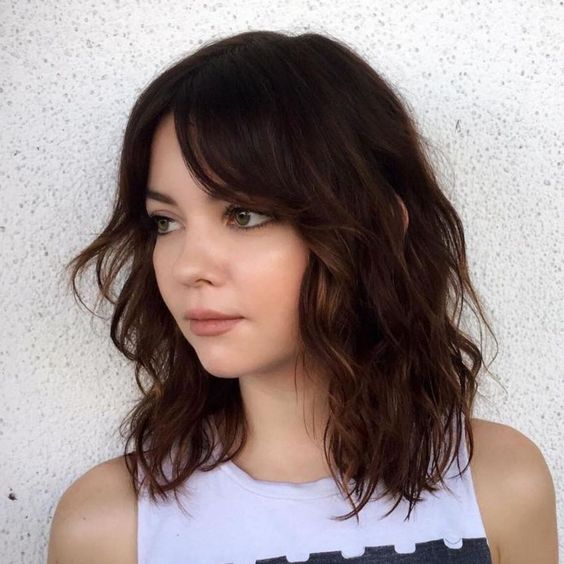 a dark brunette long bob with caramel balayage, curtain bangs and waves is a stunning solution to try