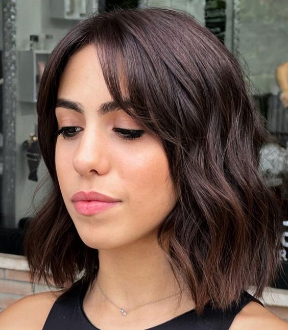 a dark brunette long bob with curtain bangs and waves is a chic and stylish idea to try