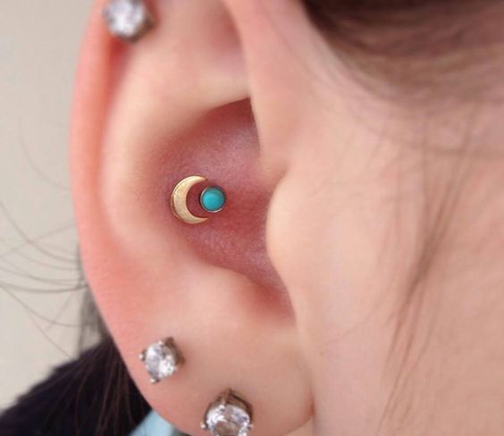 a flat, a double lobe a double conch piercing with rhinestone studs and a moon and a turquoise stud in the conch