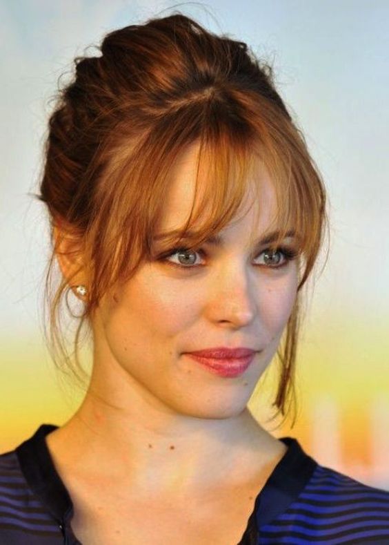 a ginger messy updo with some locks down and cool Birkin bangs that accent the face in the best way possible