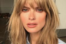 a layered honey blonde long bob with shaggy locks and with overgrown and very natural bangs is inspired by the 70s