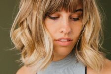 a long blonde bob with a darker root and waves plus wispy bangs for an effortlessly chic and cool look
