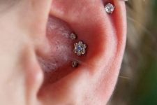 a lovely ear look with a stacked helix, a lobe and a triple conch piercing with rhinestone studs and a single hoop is a bold solution