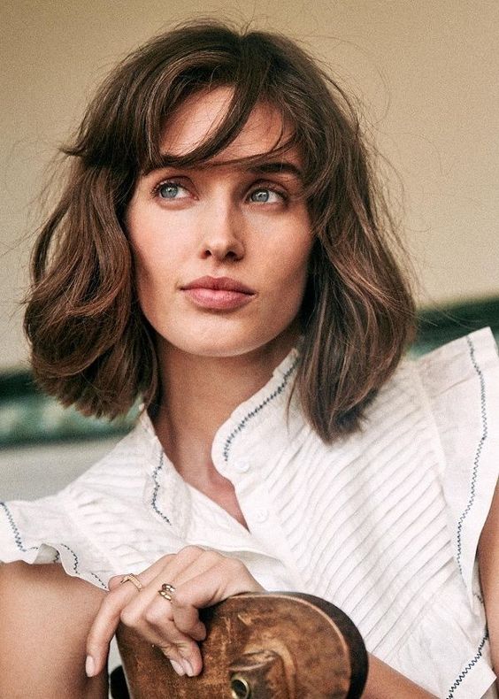 a messy brown long bob with bottleneck bangs and messy texture and volume is a chic and lovely idea