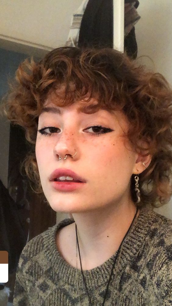a nostril plus a septum piercing done with matching a barbell and usual hoops plus stacked ear piercings