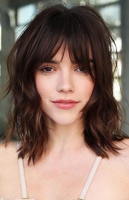 a shaggy 70s inspired long brown bob with layers and with messy overgrown bangs is a classyc idea to rock now