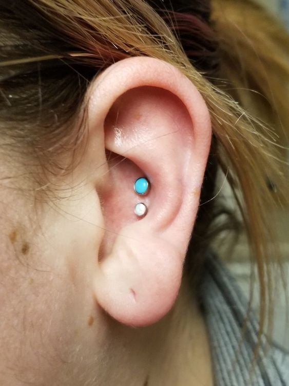 a simple and cool look with a double conch piercing with white and turquoise studs is amazing and catches an eye