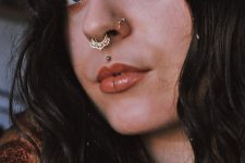 a statement septum piercing done with a gorgeous gold lace hoop, nostril piercings, a medusa piercing for a wow look