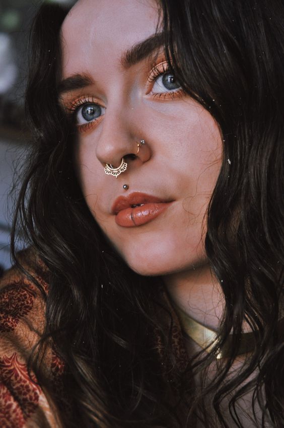 a statement septum piercing done with a gorgeous gold lace hoop, nostril piercings, a medusa piercing for a wow look