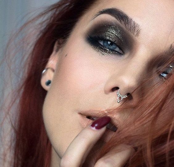 a super bold makeup with black and gold glitter smokeys and a septum piercing with a delicate and catchy hoop