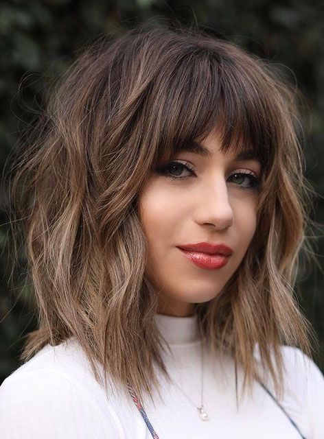 a super textural layered long bob haircut with Birkin bangs and bangs framing the face, with a slight ombre effect