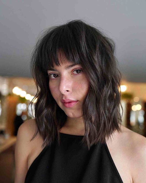 a trendy dark brown long bob with a classic blunt fringe and waves is an elegant and chic idea