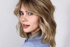a wavy blonde long bob with layers and curtain bangs to give a 70s vibe to the look
