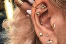 beautiful boho ear styling with a double conch, flat, helix, tragus and stacked lobe piercings, all done with beautiful gold studs and a couple of hoops