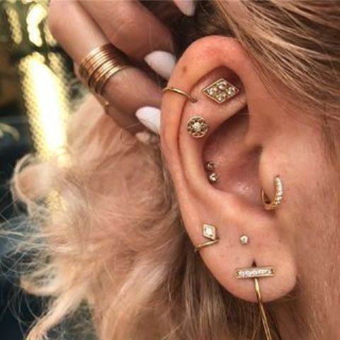 beautiful boho ear styling with a double conch, flat, helix, tragus and stacked lobe piercings, all done with beautiful gold studs and a couple of hoops