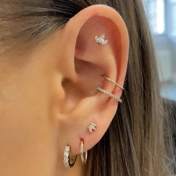 beautiful ear styling with a pretty flat piercing with a rhinestone stud, a double conch piercing with hoops, a triple lobe piercing with hoops and a stud