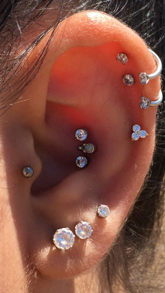 bold and glam ear styling with a triple conch, triple lobe, tragus, stacked helix piercings done with rhinestone studs and hoops is wow