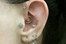 catchy ear styling with stacked lobe piercings with stud hoops, a tragus, forward helix, daith and a double conch piercing done with hoops and studs