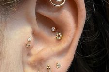glam ear styling with stacked lobe piercings, a double conch piercing, a double tragus, a helix piercing all done with gold studs and hoops