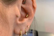 pretty Halloween ear styling with stacked lobe peircings done with spike hoops, a double conch piercing with a skull, a tragus and a flat piercing