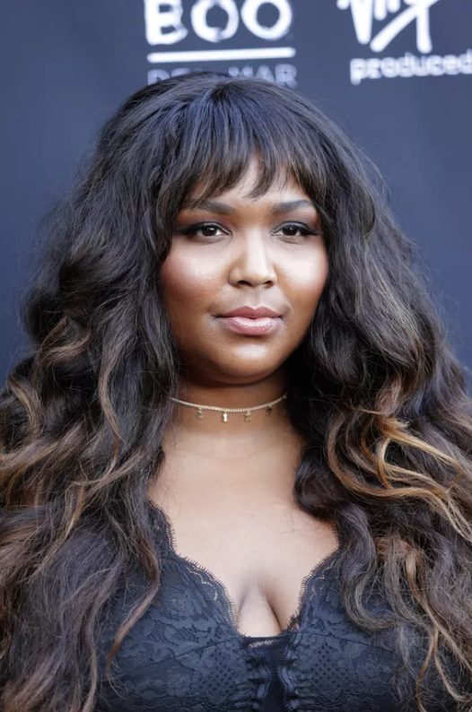 these bangs have a slight wave to them that mirrors the loose curls cascading past her shoulders, and sun-kissed balayage adds even more vacation vibes