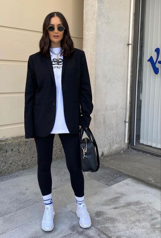 a sport chic monochromatic look with a white tee, black leggings and a black oversized blazer, white socks and trainers, a black bag