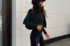 08 a sport chic outfit for spring – black leggings, a green long sleeve crop top, a black quilted vest, a black cap, white trainers
